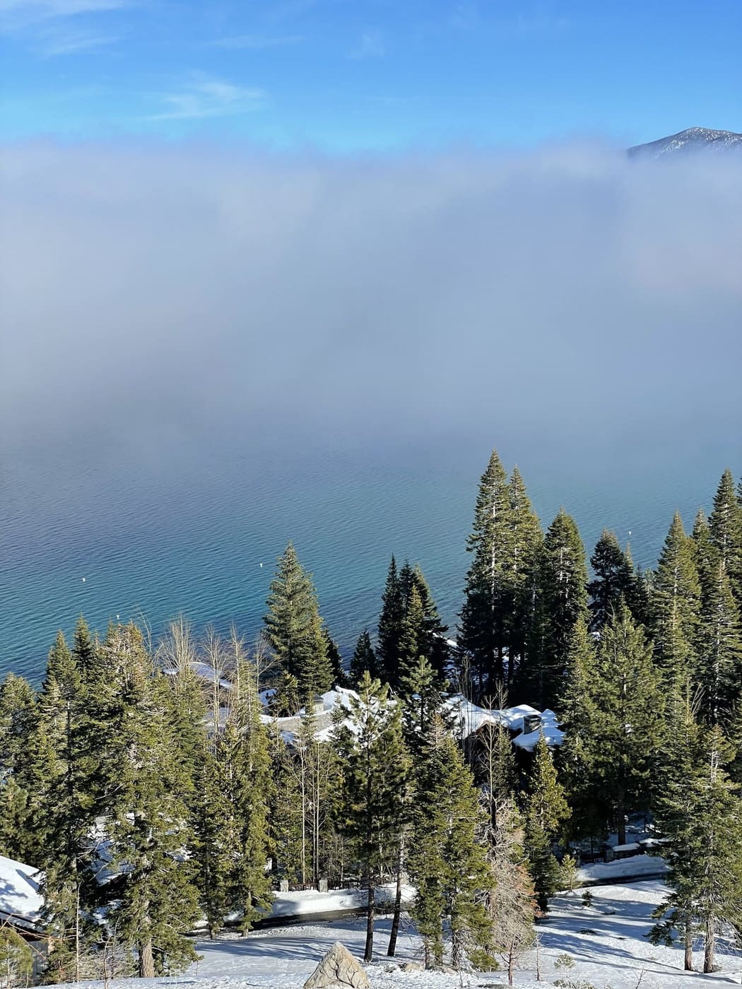 Fog rolling over Lake Tahoe with snow-covered lakefront homes